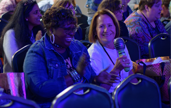 two woman smiling in an audience