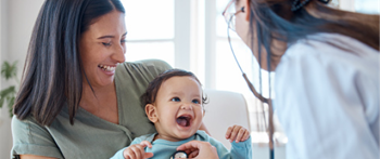 a doctor examining a smiling baby